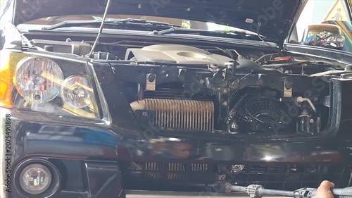 Professional auto mechanic calmly inspecting and servicing a vehicle air conditioning system in a modern, well-equipped auto repair garage.