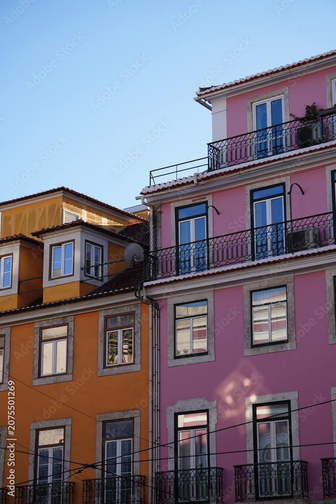 Obraz premium Colorful Orange and Pink Apartment Buildings with Iron Balconies Against Blue Sky, Lisbon, Portugal
