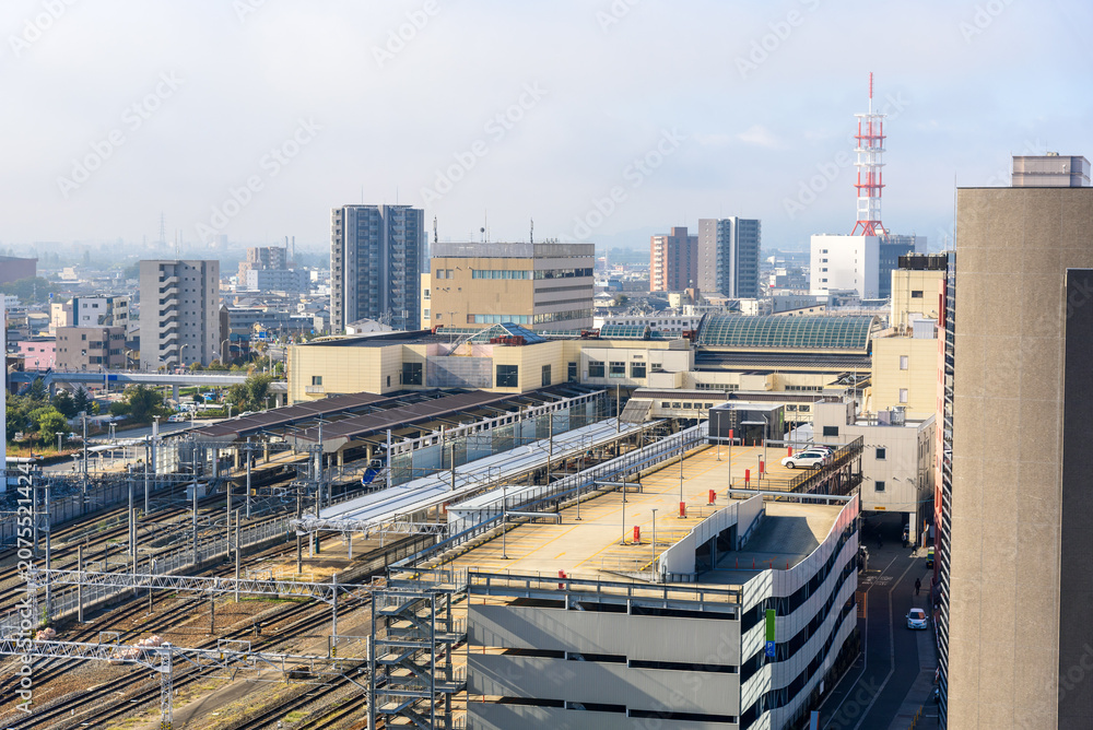 Fototapeta premium Elevated view of a train station surrounded by multi-storey car parks and apartment buildings in a city centre on a foggy autumn morrning