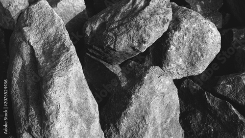 Photos Monochrome large stone close-up with rough mineral faces, deep shadow gaps, chalky stains, and raw natural texture
