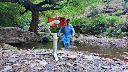 a content creator stands outdoors, installing a stabilizer gimbal onto their mobile phone for smooth natural video recording