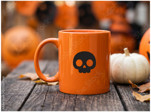 Orange halloween mug with skull icon on rustic wooden table.