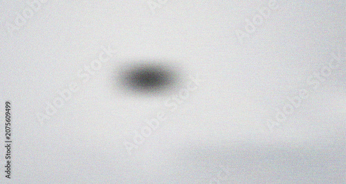 Konstfotografi Central dark blurred circle on a light grey grainy surface creating a mysterious
