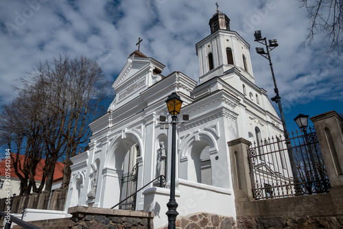 White historic church with bell tower and cloudy sky