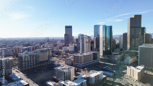 Panoramic views capture interplay between mature treelined streets evolving commercial density. Vibrant morning illumination highlights varied roof geometries across urban Denver, CO landscape