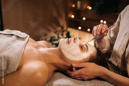 Photos A cosmetologist makes a mask for a woman's face to rejuvenate the skin