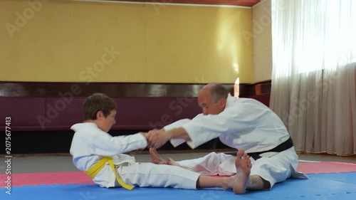 A trainer and a little athlete perform stretching exercises