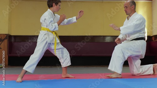 A coach and a little athlete perform a stand-up jump from a sitting position