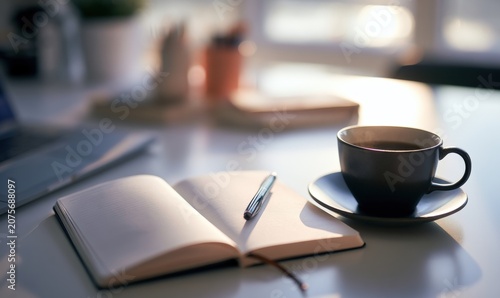 Cup of coffee next to open notebook on a desk