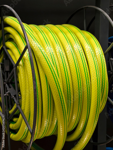 Tableau sur toile Yellow hose with green stripes rolled into a coil is presented in a retail store