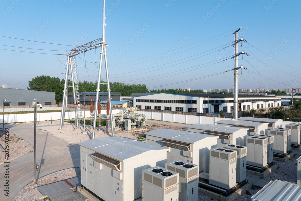 Fototapeta premium Outdoor substation with power equipment transmission towers and high voltage lines under clear blue sky