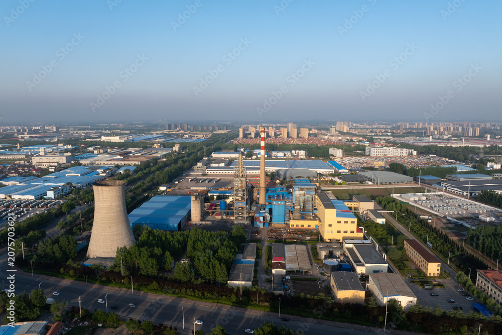 Fototapeta premium Industrial complex featuring cooling tower smokestacks factory buildings and infrastructure under clear sky