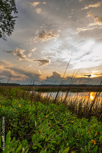 Sunset over a river with clouds and grassland in the evening
