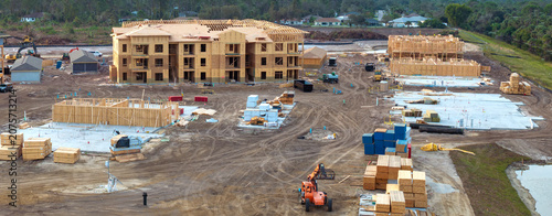 Unfinished frames of apartment condos with wooden roofs under construction. Development of residential housing in US suburbs. Real estate market in the USA