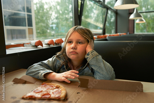 Canvas-taulu A primary school-aged girl sits at a table in a pizzeria