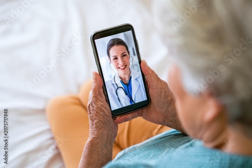 Senior woman having a telemedicine video consultation with female doctor on smartphone at home