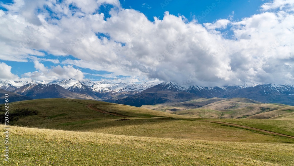 Fototapeta premium Dzhily-Su, Russia - June 4, 2026: View of the Caucasus Mountains along the road to Dzhily-Su, showing mountain peaks, valleys, winding road, open landscapes, and scenic natural surroundings.