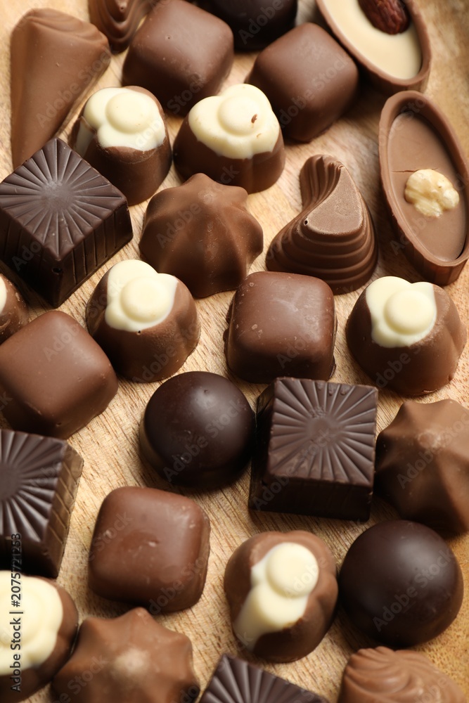 Obraz premium Delicious chocolate candies on wooden table, above view