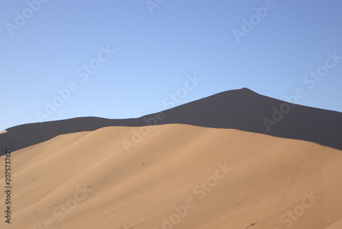 Massive Sand Dunes with Sharp Ridgeline and Deep Shadow Contrast Against Clear Blue Sky in Namib Desert