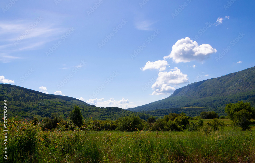 Obraz premium Lush Green Mountain Slopes Under Majestic Blue Sky with Clouds