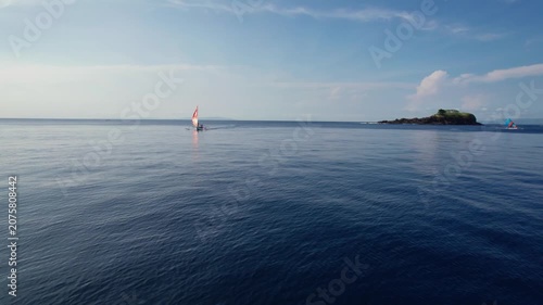 Aerial View of Traditional Outrigger Sailboat with Colorful Sail on Clear Tropical Ocean