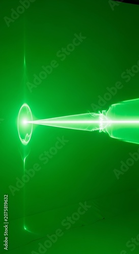 Intense green luminous beam interacts with an ethereal circular field against a dark backdrop