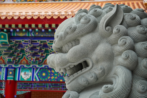 Stone lion guardian statue in front of ornate traditional Chinese temple architecture