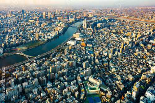 Aerial view of Tokyo from Skytree observatory capturing vast urban landscape, Sumida River, and skyline under warm sunset haze and atmospheric light.