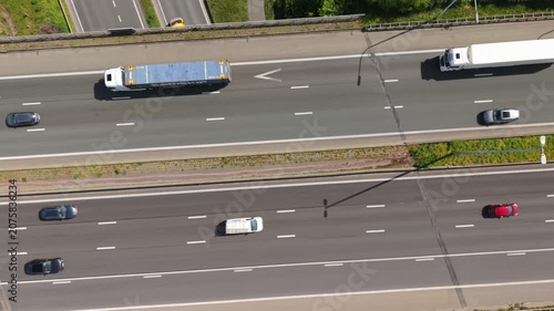 Aerial perspective captures various vehicles, including cars and trucks, moving along a busy highway, highlighting the continuous flow of traffic and clear road markings in a vibrant outdoor setting