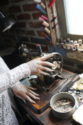 Artisan working on a vintage sewing machine showing hands with intricate lace sleeves in a rustic workshop