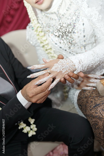 Intricate white henna adorns a bride's hand at a cultural wedding ceremony, symbolizing beauty and tradition. captures this elegant moment of heritage