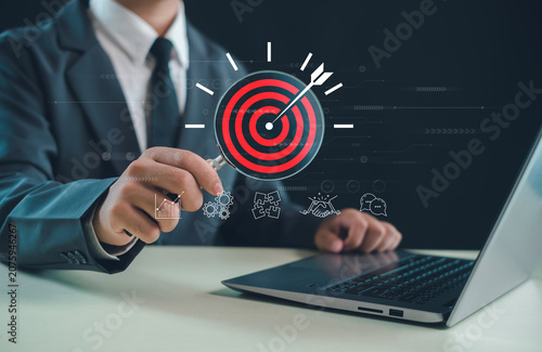 Фотография Business professional analyzing a target through a magnifying glass, representing goal achievement, strategic planning, market analysis, business growth, performance tracking, and success