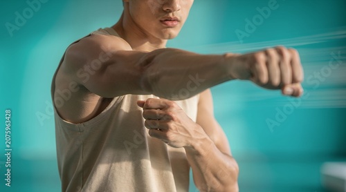 Athletic Male Martial Artist Punching in Motion Against Teal Backdrop.