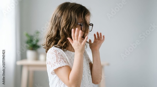 Woman in White Lace Top Adjusting Glasses in Bright Indoor Setting.