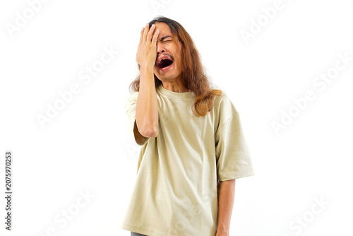 Schilderij op canvas A young Asian man with long hair expressing frustration or disappointment by covering his face with his hand, isolated on a clean white background