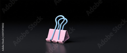 Pink and blue binder clip on black surface with shadow and reflection.