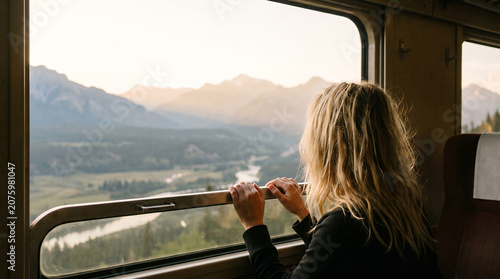 Woman gazing at mountain landscape from train window
