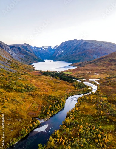 Serene river winding through lush green valley with mountains.