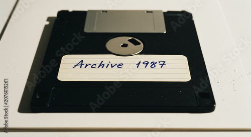 Vintage 3.5-inch floppy disk with handwritten archive label from 1987 on a white surface