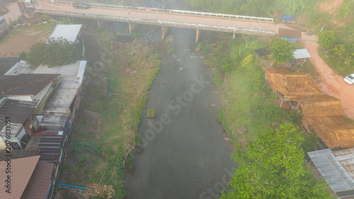 Foto An aerial photograph shows morning mist lingering over a bridge crossing a canal flowing through Saphan Village, Nan Province