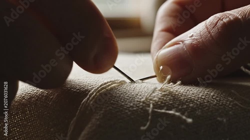 Macro of needle and thread sewing coarse fabric.