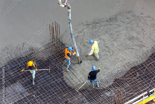 Fotografi Construction workers checking concrete level and pouring monolithic slab