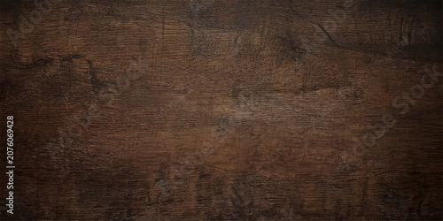 A textured, dark brown wooden surface with visible grain patterns and subtle variations in color, providing a rustic and natural background.