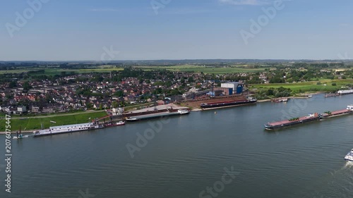 Aerial view of a loaded barge sailing on a river past a town