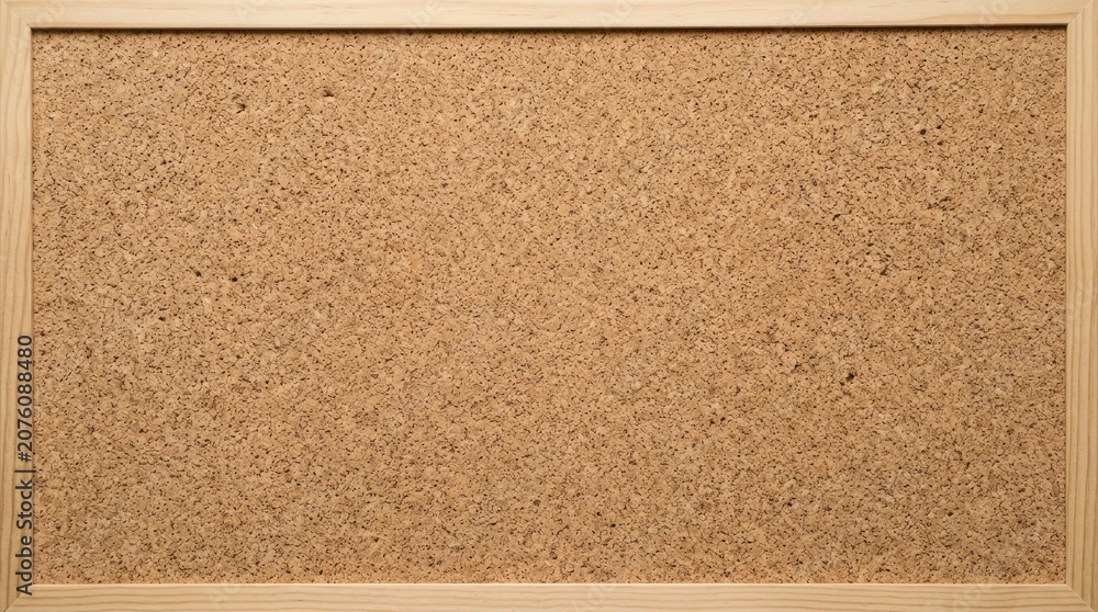 Fototapeta premium A light-colored wooden frame surrounds a corkboard. The corkboard has a natural, textured surface.