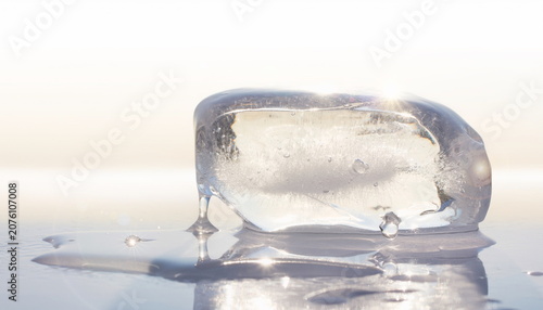 Horizontal crystal ice block melting on white surface 横長の透明な氷ブロックの背景素材