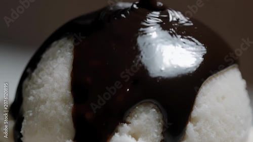 Creamy vanilla ice cream topped with rich chocolate sauce drizzled over the surface, showcasing a close-up view of the dessert's texture and glossy finish