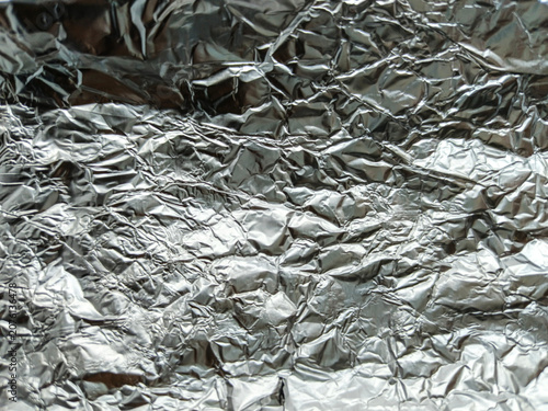 Foto Metallic surface displays intricate folds and shadows creating a textured background