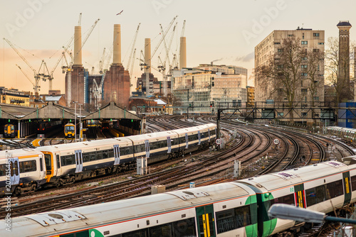 London trains near Battersea Power Station

Description:
Commuter trains and railway tracks near Battersea Power Station in London with construction cranes, new development and evening light, illustra