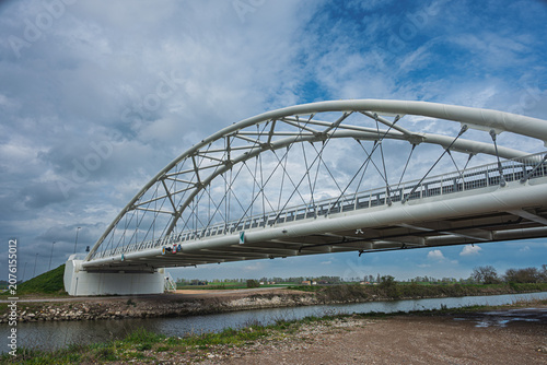 a modern metal bridge inside the Polesine campaigns with a cloudy sky in the background, Rovigo, Italy 